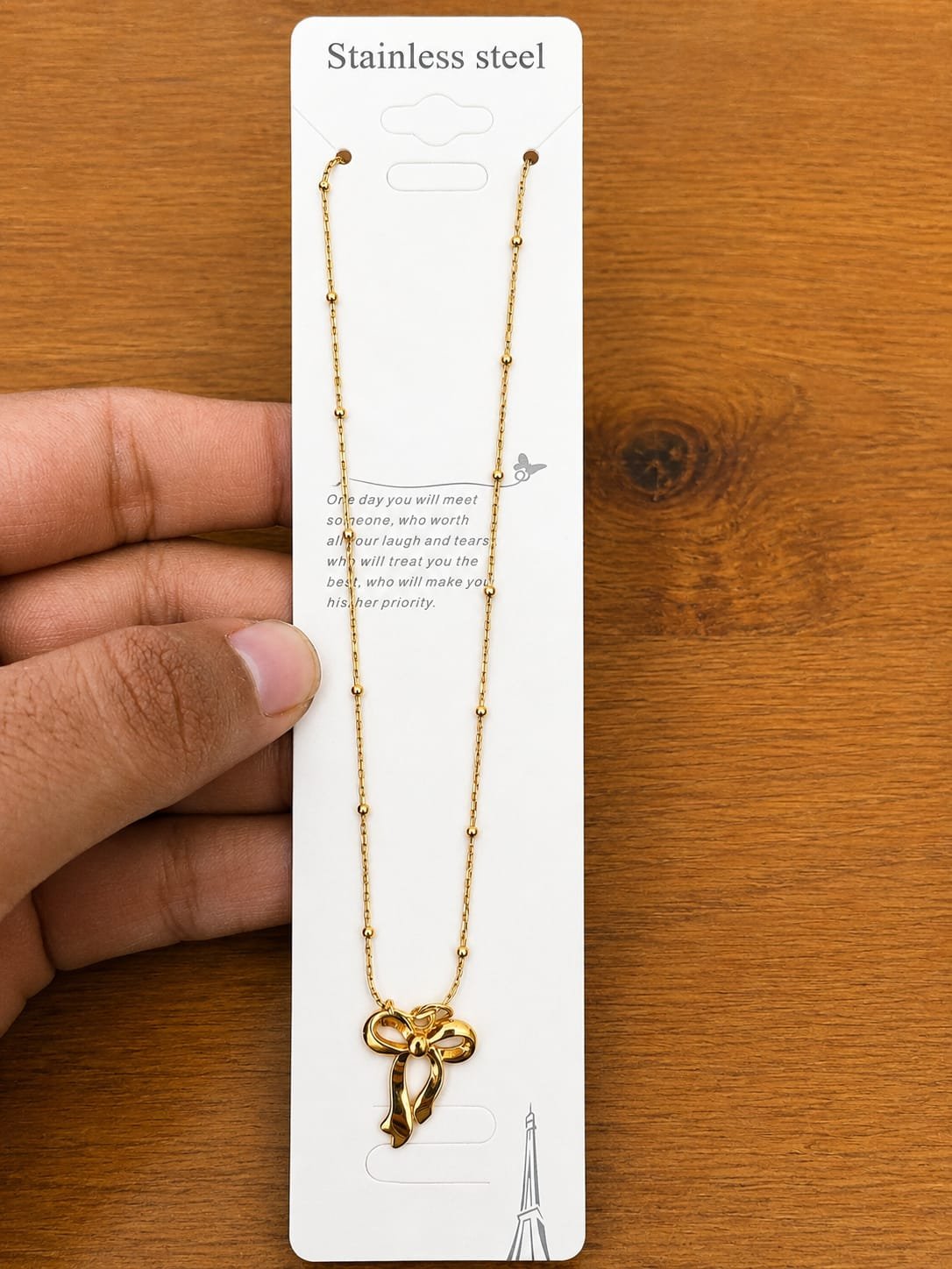Gold-tone open ribbon bow pendant necklace on a ball-station chain