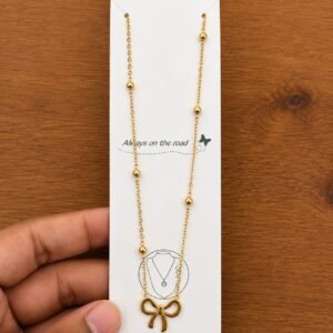 Gold-tone outline bow pendant necklace on a ball-station chain