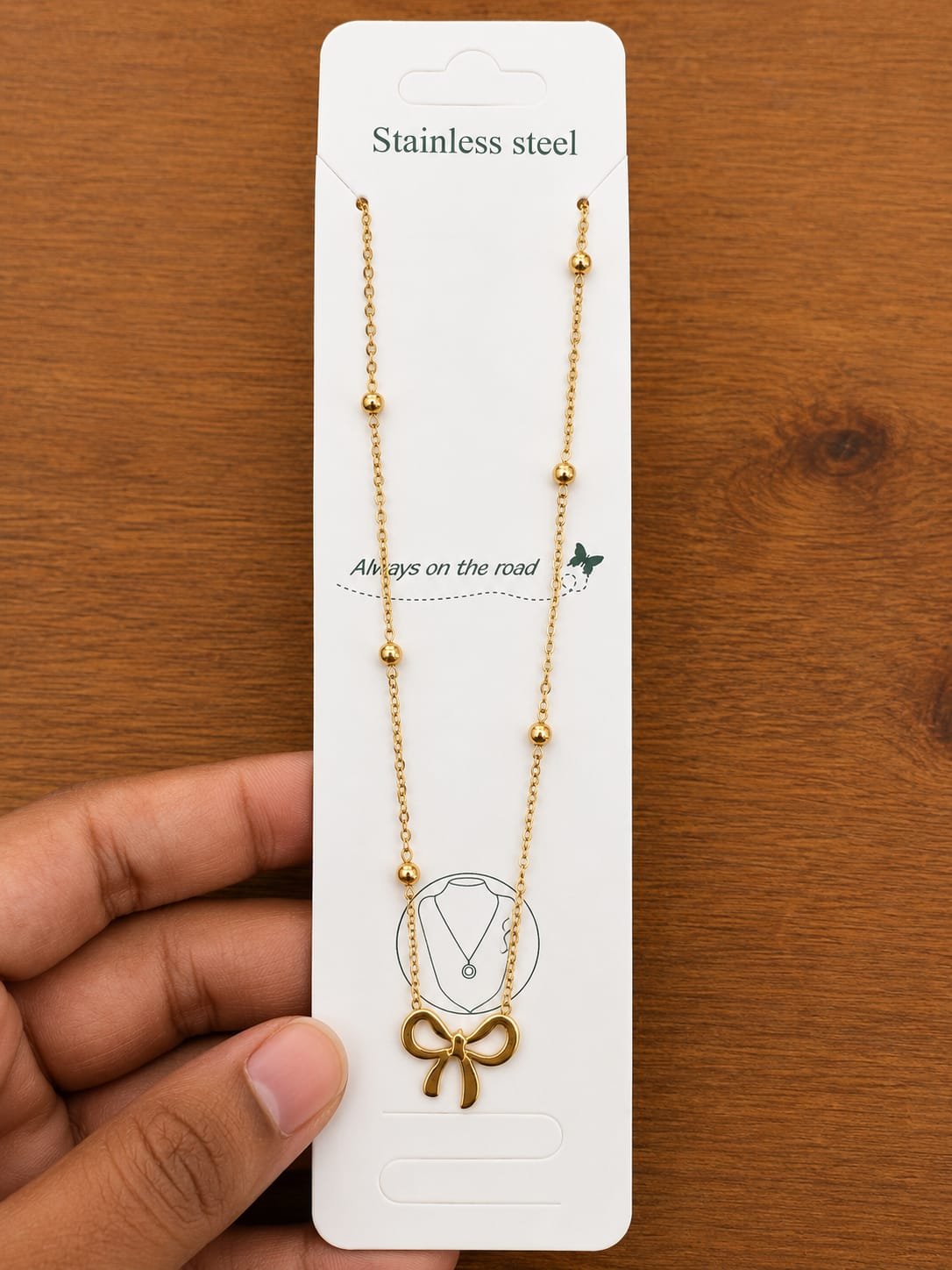 Gold-tone outline bow pendant necklace on a ball-station chain