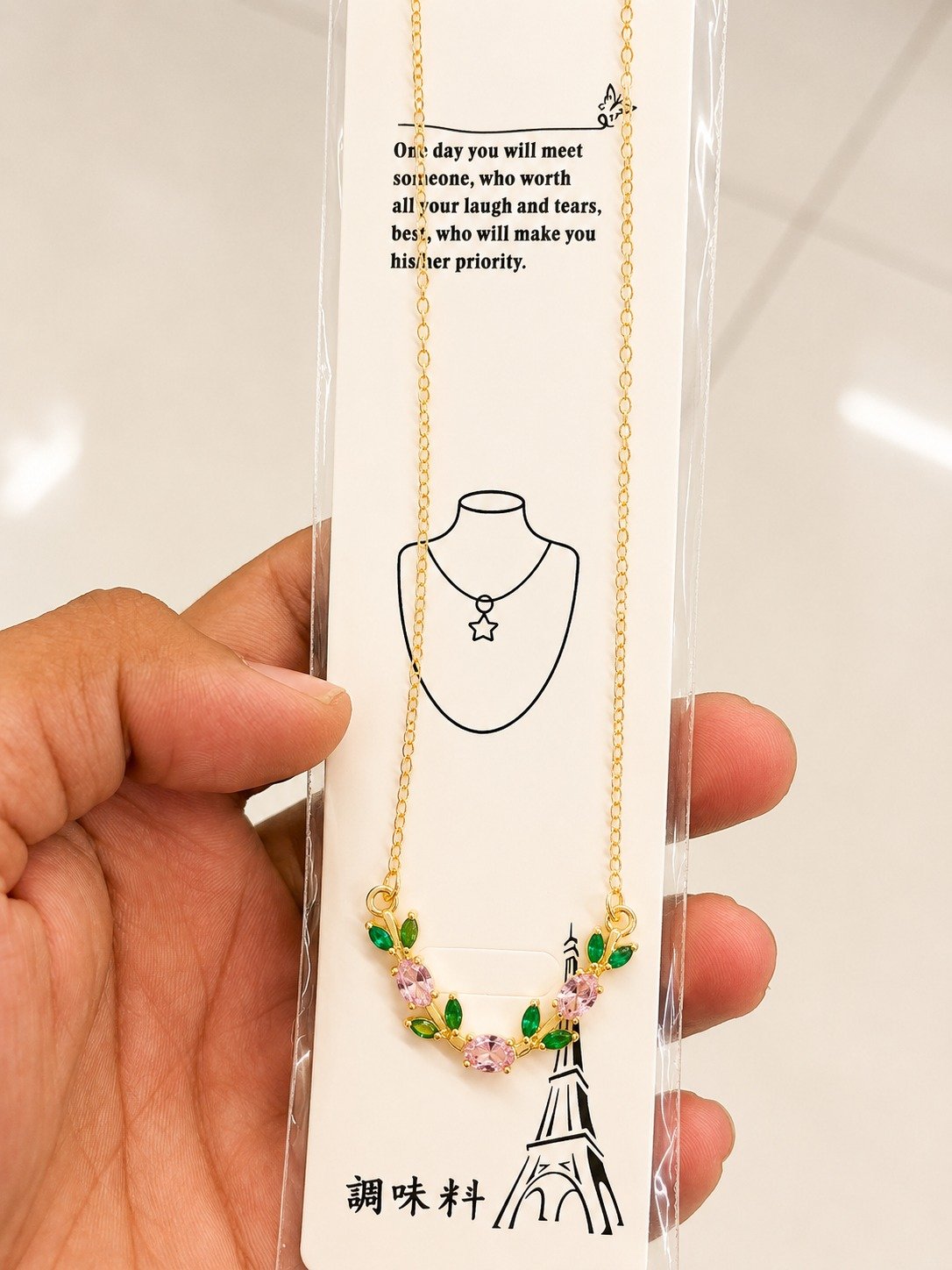Gold-tone flower necklace with pink stones and green leaf accents